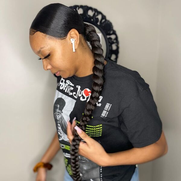 Low Sleek Middle Part Braid Ponytail - A woman with airpods wearing a black printed shirt