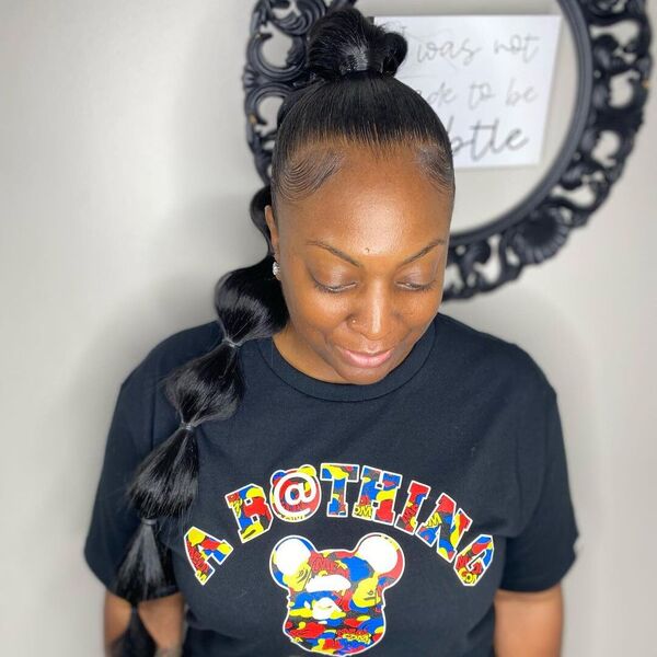 Sleek Ponytail with Weave and Bubbles - A woman wearing a blue printed shirt